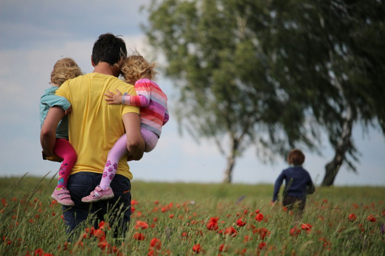 Bien choisir les couches de bébé sans exploser son budget : conseils de parents avertis man carrying to girls on field of red petaled flower