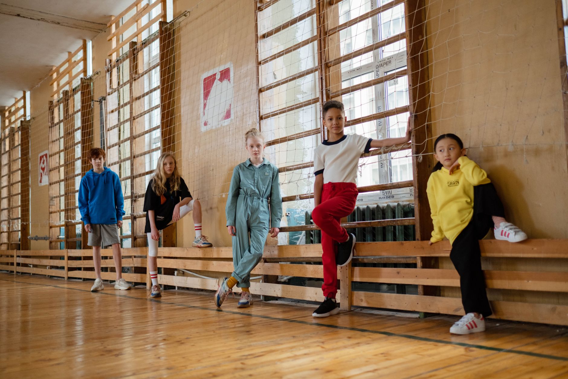 Groupe d'enfants divers posant à l'intérieur dans un gymnase, montrant l'amitié et l'unité.