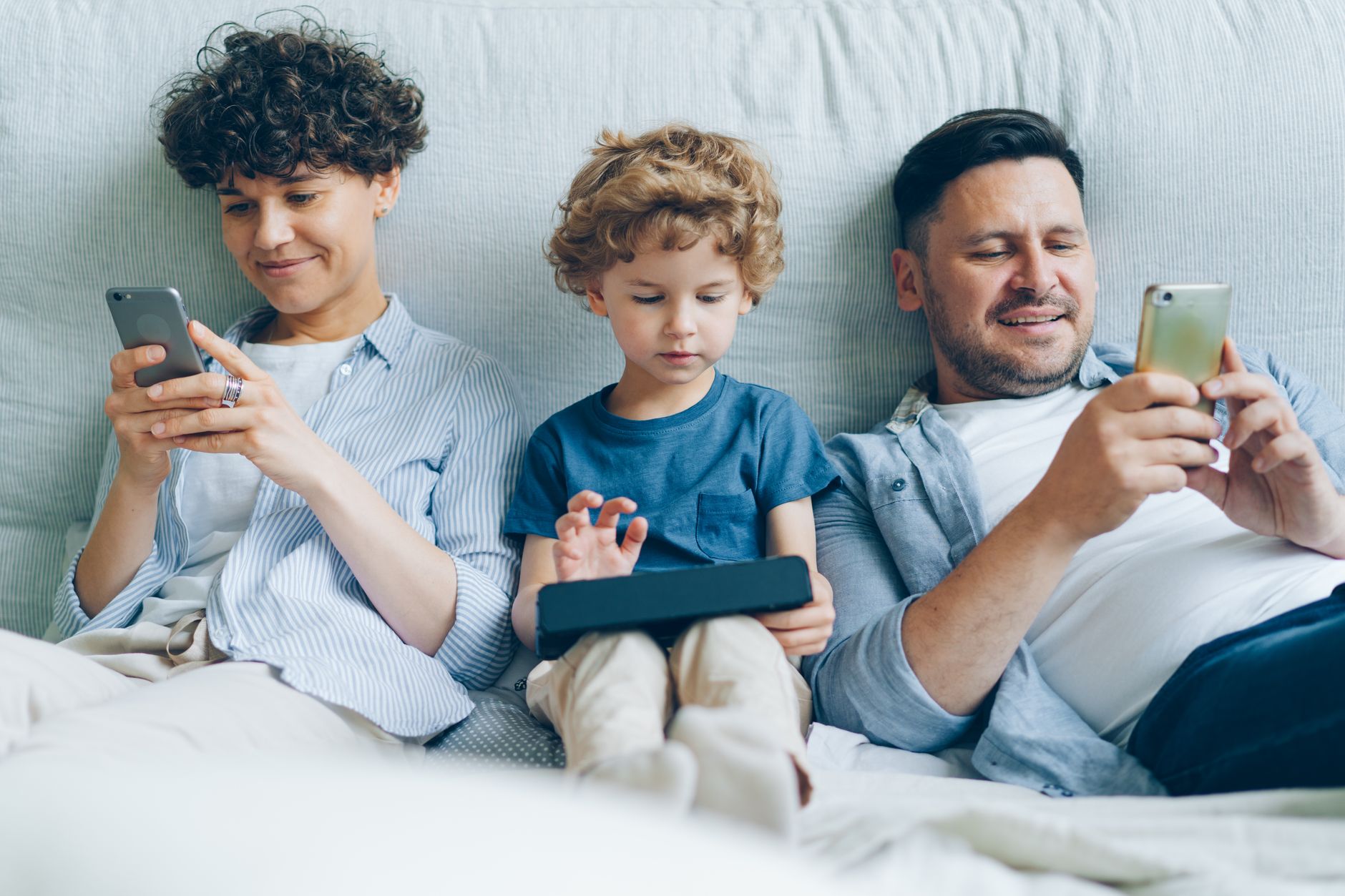 Famille heureuse profitant d'un moment d'écran ensemble sur un canapé confortable à la maison.