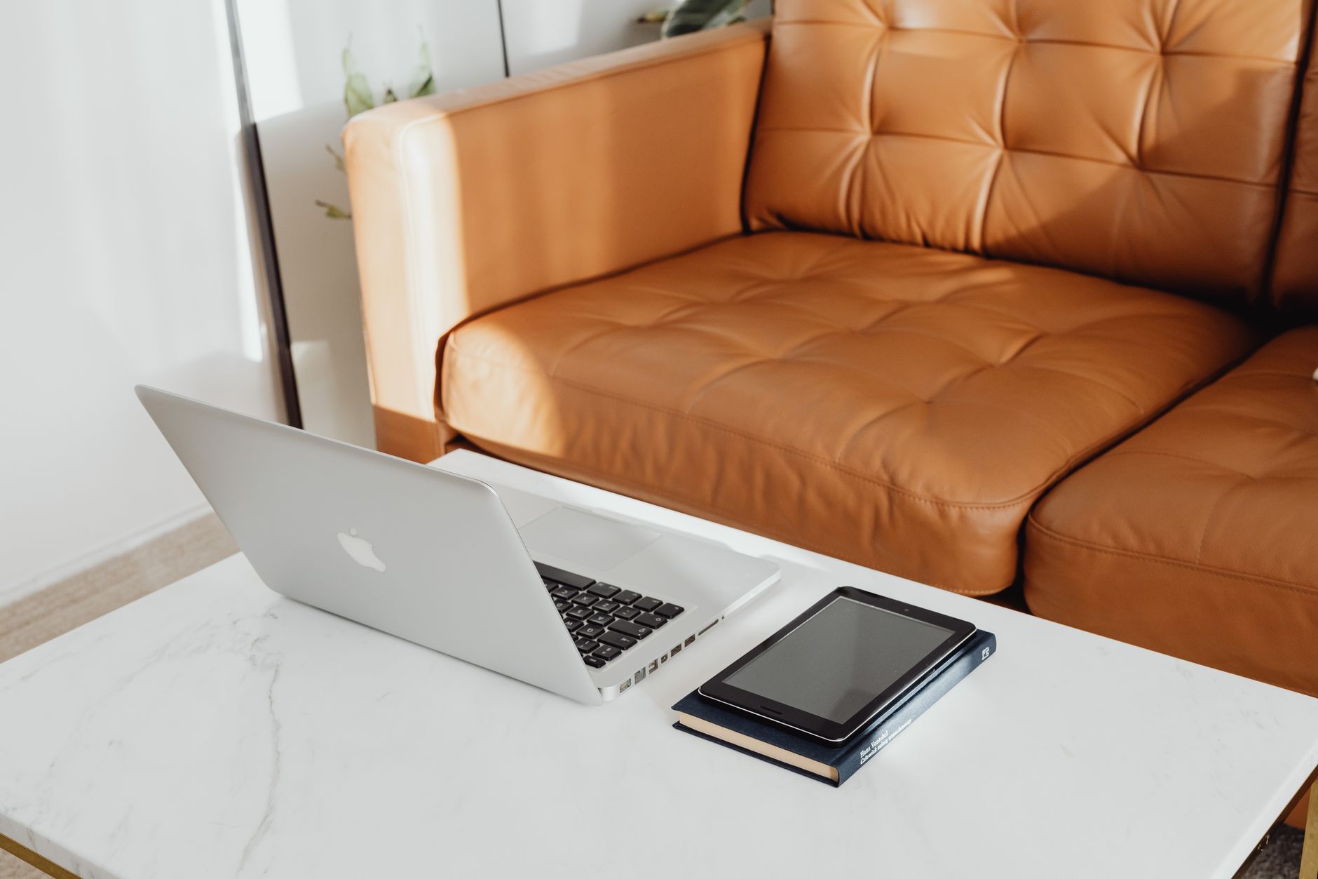 Un ordinateur portable et une tablette sur une table devant un canapé