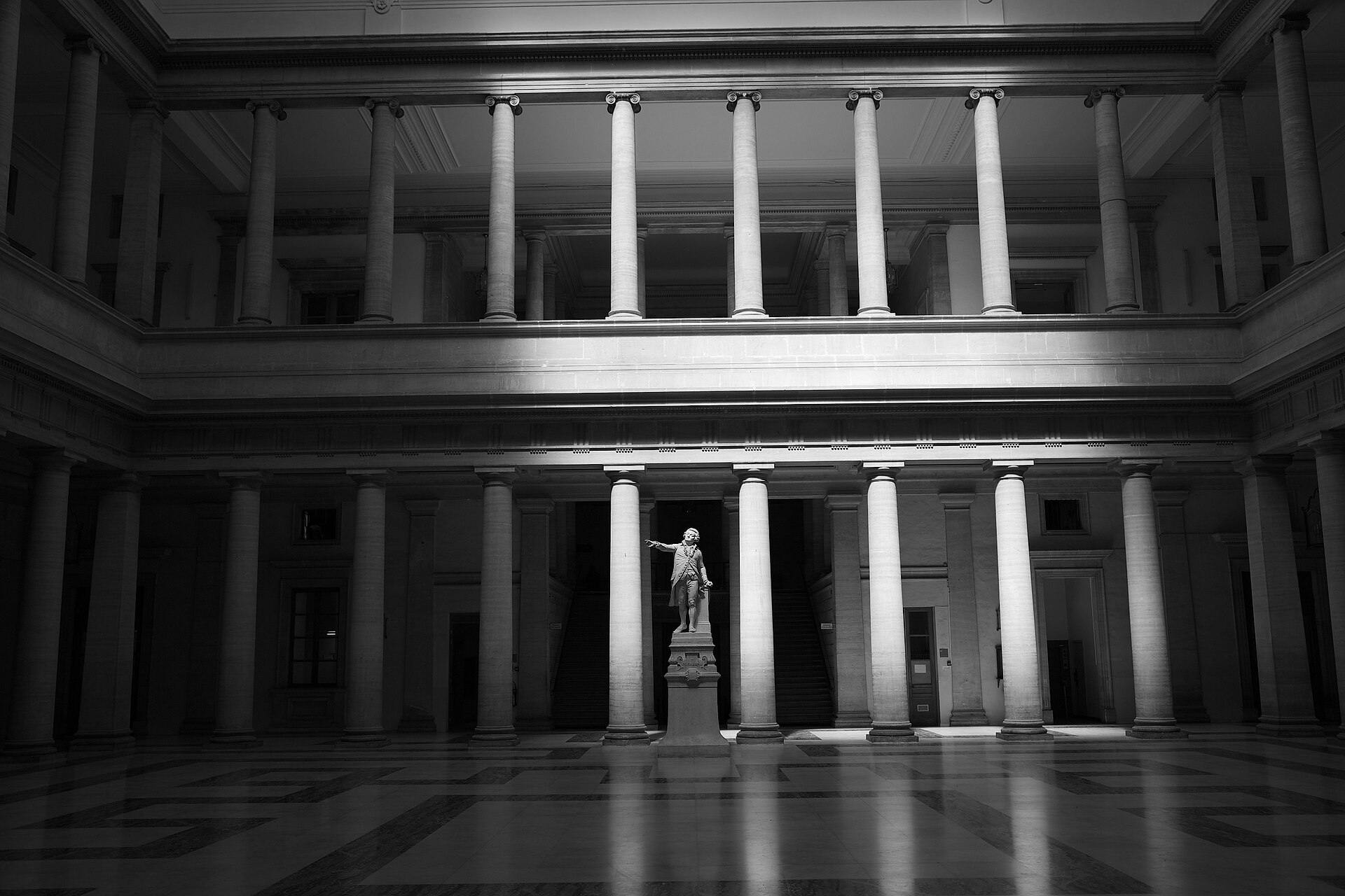 Salle des pas perdus du palais de justice d'Aix-en-Provence en noir et blanc, colonnes éclairées par une lumière latérale